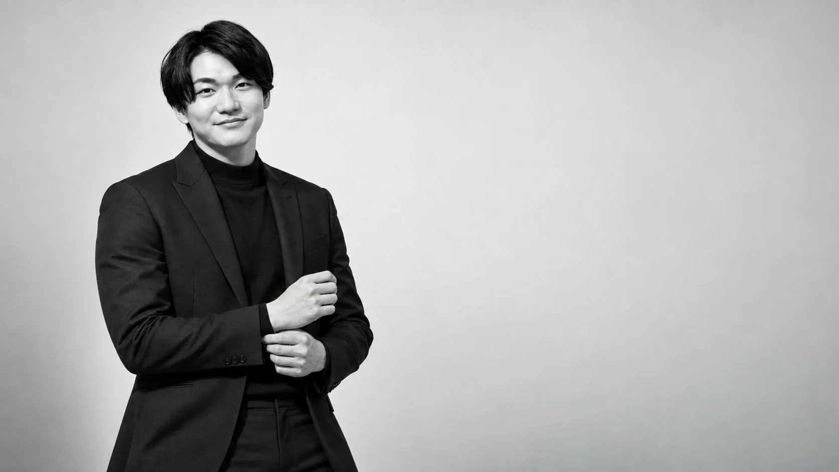 黒いジャケットを着たGENTLE代表の立ち姿