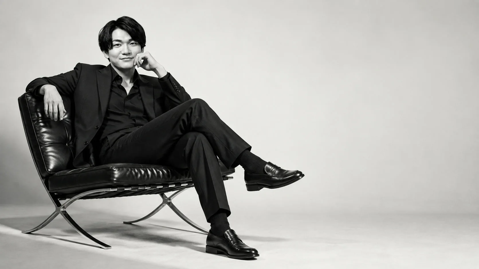 黒いスーツで椅子に座るGENTLE代表のポートレート